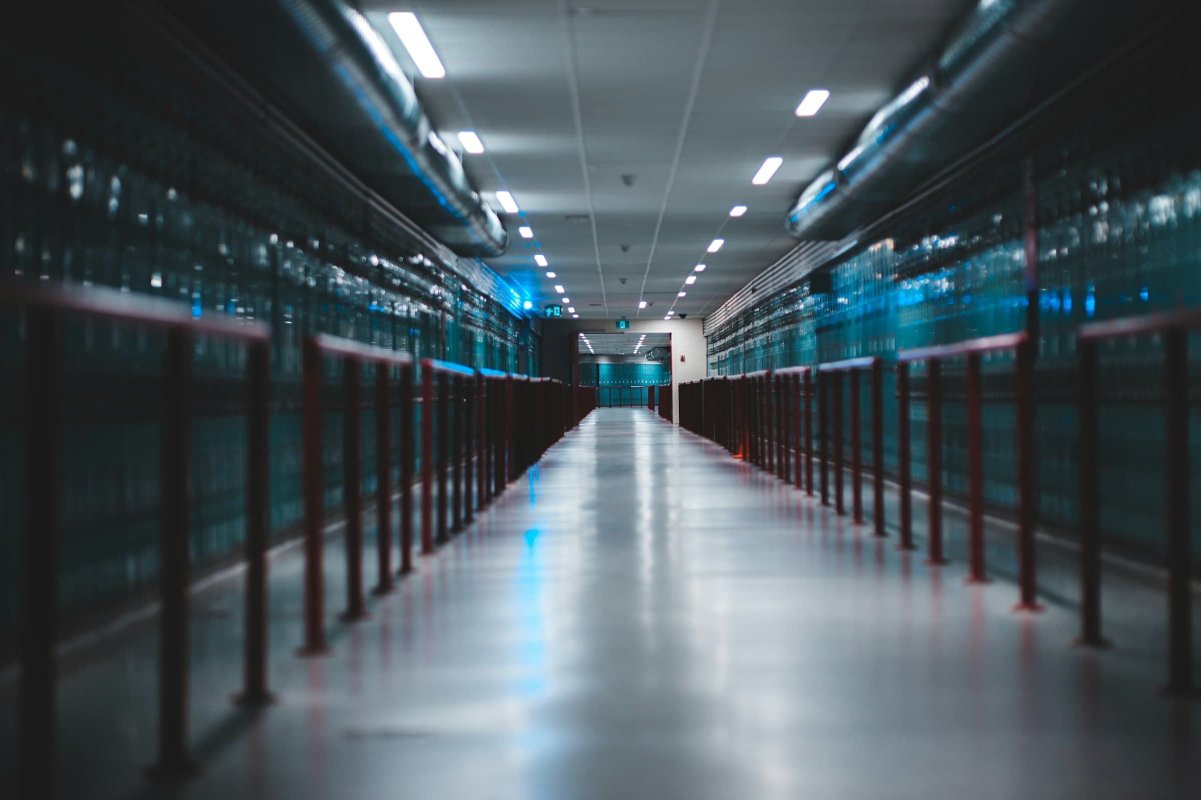 A long, softly lit corridor between rows of server racks in a data center