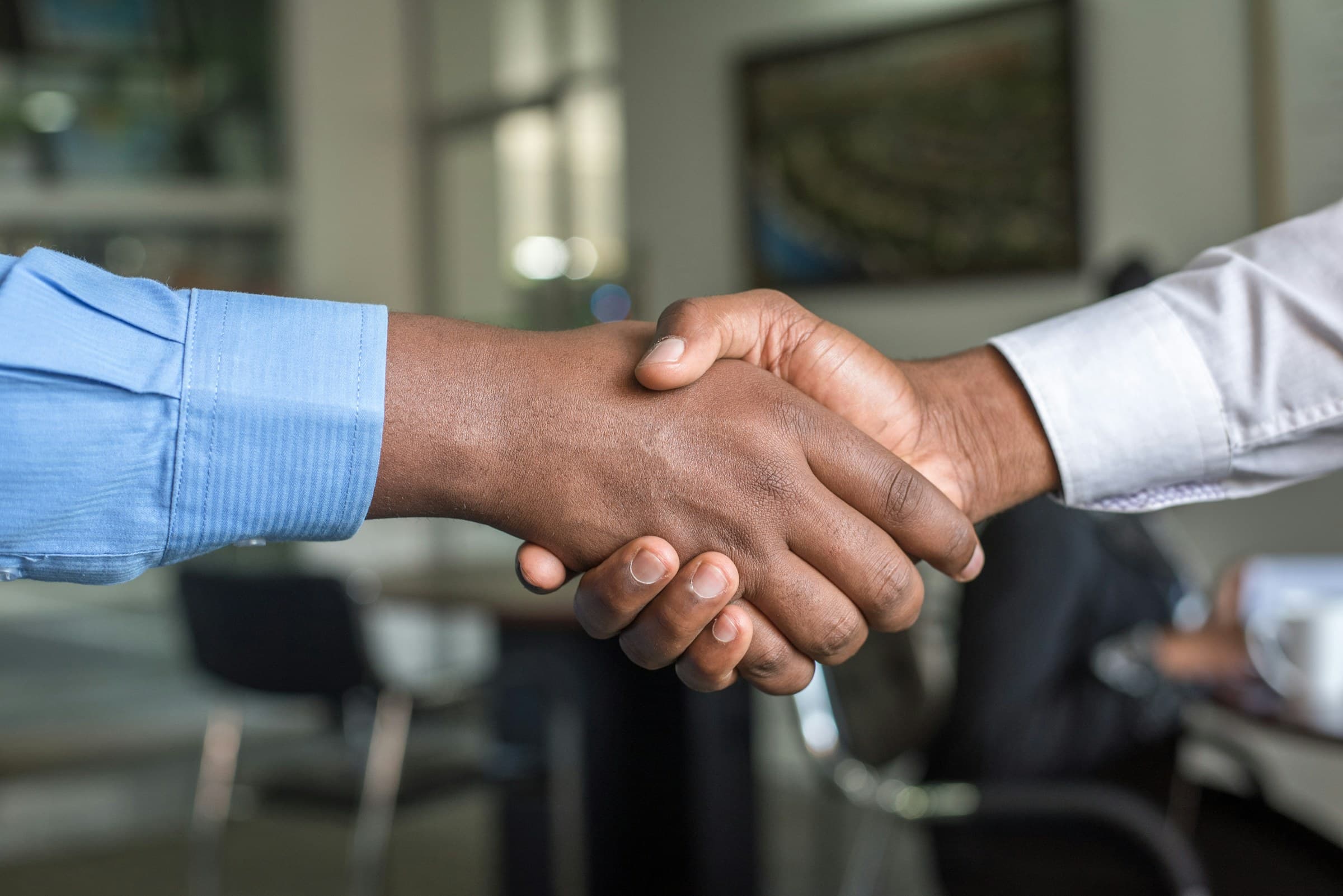Close-up of two people shaking hands in an office